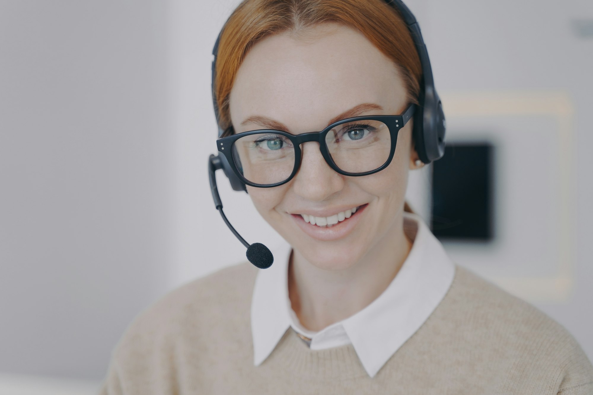 Online consultant of call center. Young woman in earphones provides information by telephone.